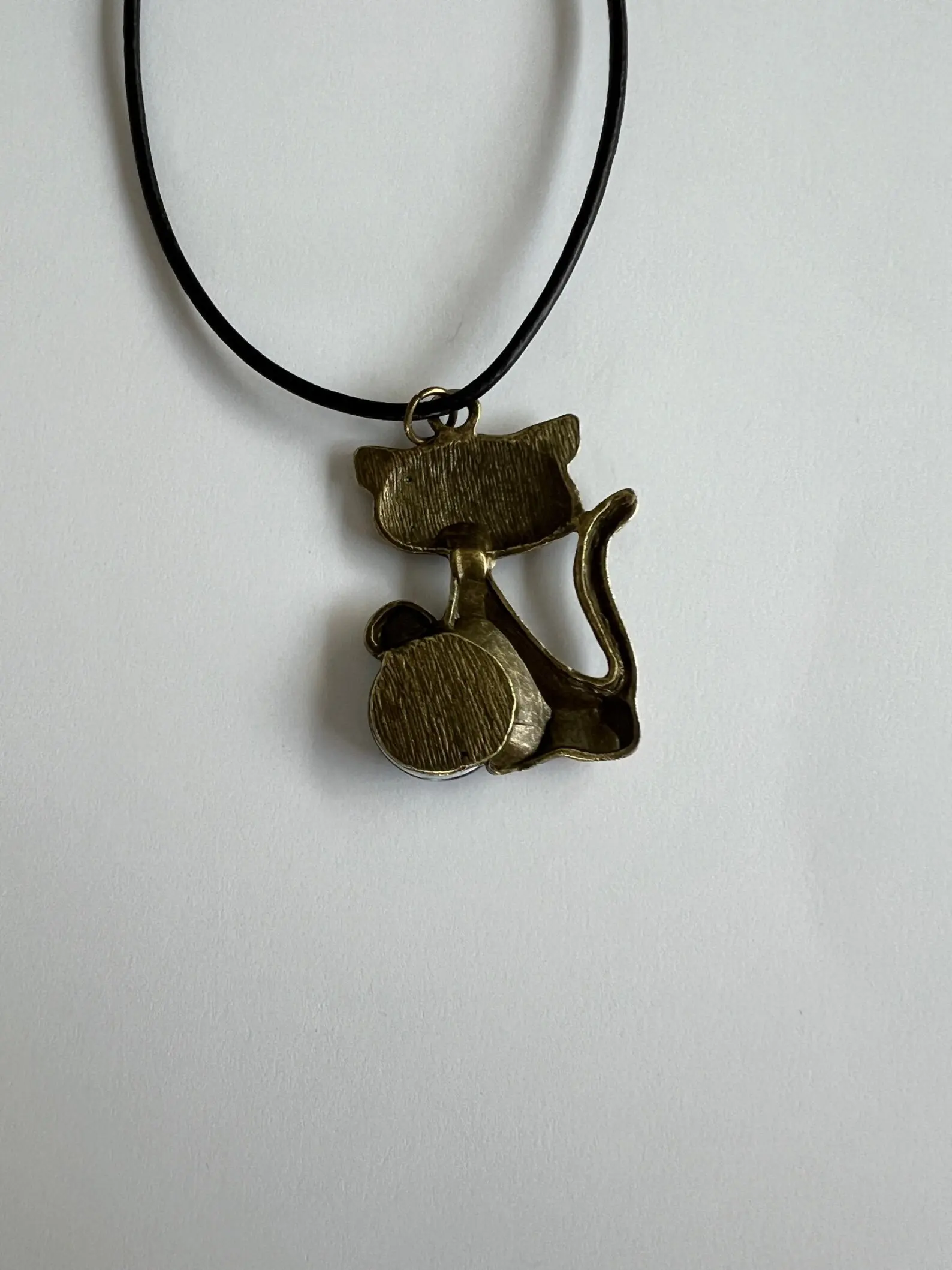Bronze cat pendant with black string.