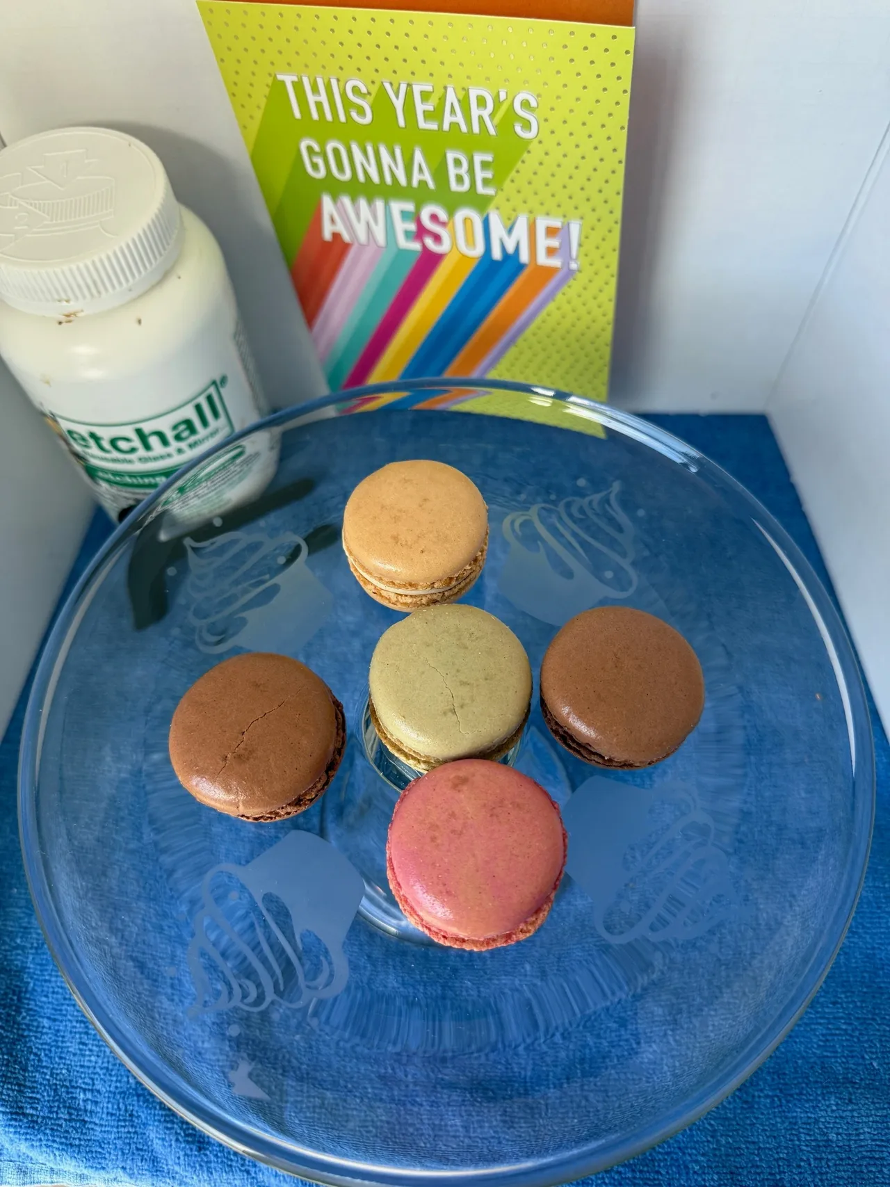 Macarons on glass plate with colorful card.