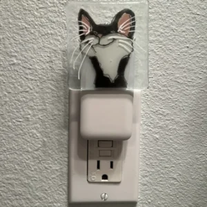 Smiling cat night light plugged into wall outlet